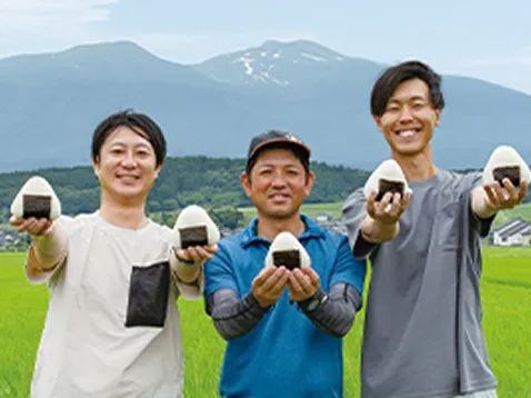 畑でおにぎりを持っている3人の農家