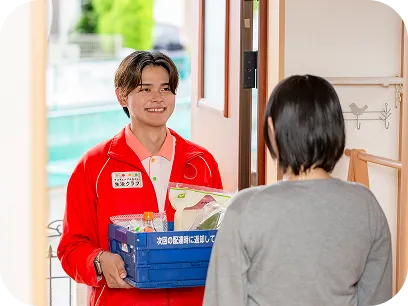 玄関先で配達員から荷物を受け取る様子